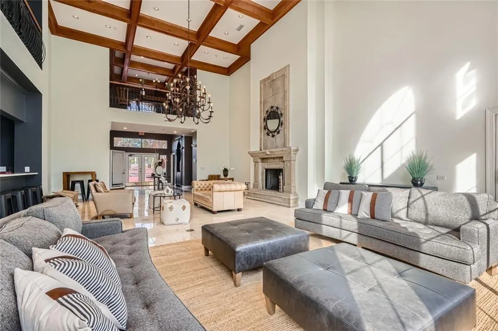 Living room featuring coffered ceiling, beamed ceiling, a chandelier, a towering ceiling, and a fireplace