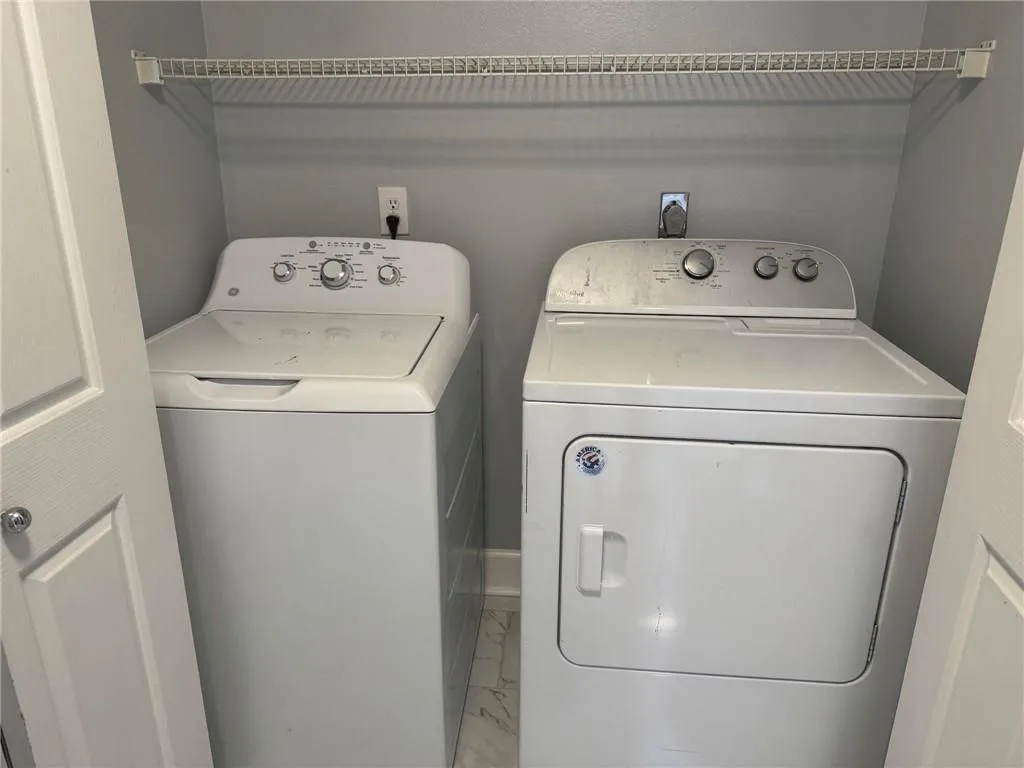 Laundry area featuring washer and dryer and marble look tiles