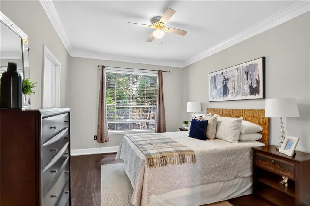 Bedroom featuring ornamental molding, dark wood-style floors, and a ceiling fan
