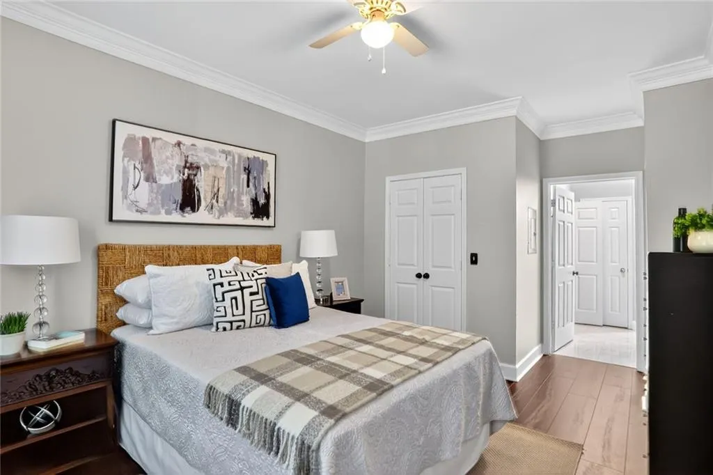 Bedroom featuring wood finished floors, crown molding, a closet, and ceiling fan