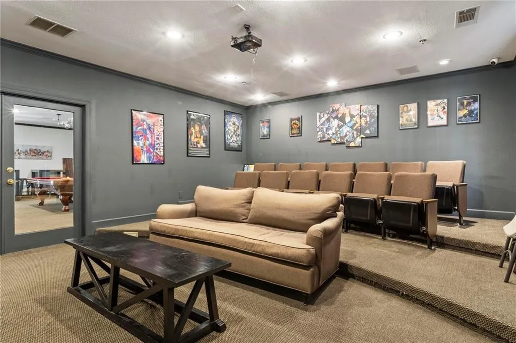 Carpeted home theater featuring ornamental molding, recessed lighting, and a textured ceiling
