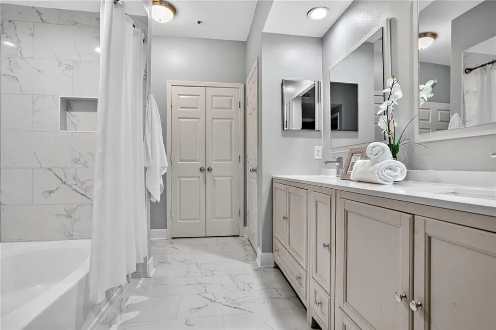 Bathroom with marble look tile flooring, double vanity, and shower / tub combo