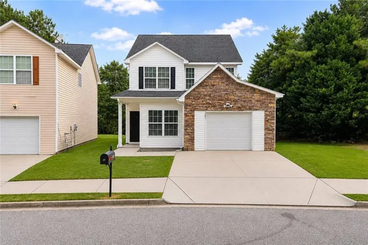 Two-story residence featuring white siding and a prominent stone facade accenting the single-car garage