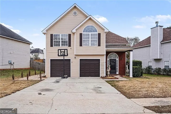 Two-story residence with light-toned siding, a covered entry, and a two-car garage with dark paneled doors