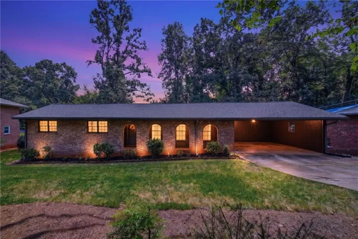 Brick exterior with arched entryways, covered carport, and established landscaping