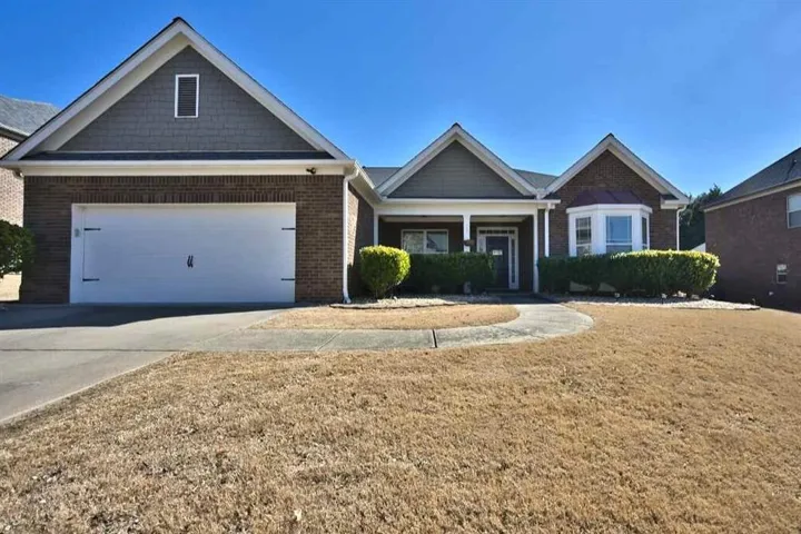 Brick and siding exterior with a prominent bay window, covered porch, and an attached two-car garage