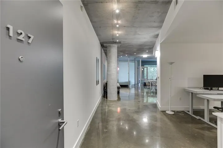 Concrete flooring, exposed concrete ceiling, recessed lighting, and white walls