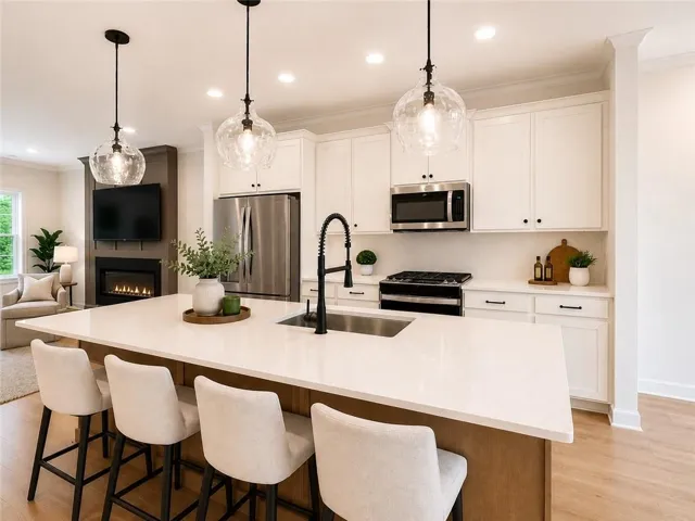 Photo is virtually staged. Beautifully appointed kitchen featuring crisp white cabinetry, a warm natural wood island, quartz countertops, stainless steel appliances, and statement pendant lighting.