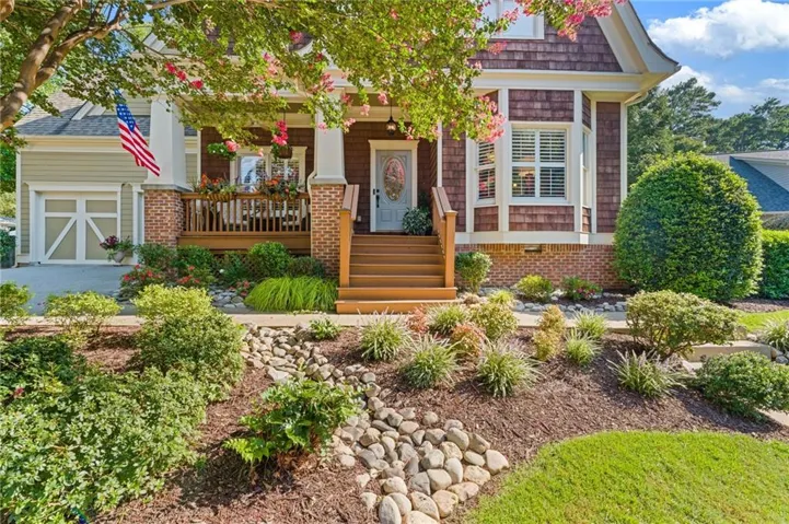 Front exterior with a covered porch, wood-finish stairs, and detailed cedar shake siding