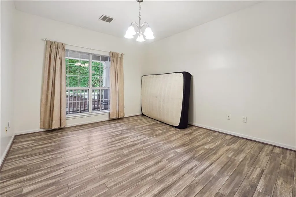 Empty room with a chandelier and wood-type flooring
