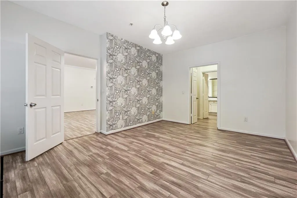 Unfurnished room with hardwood / wood-style flooring and an inviting chandelier
