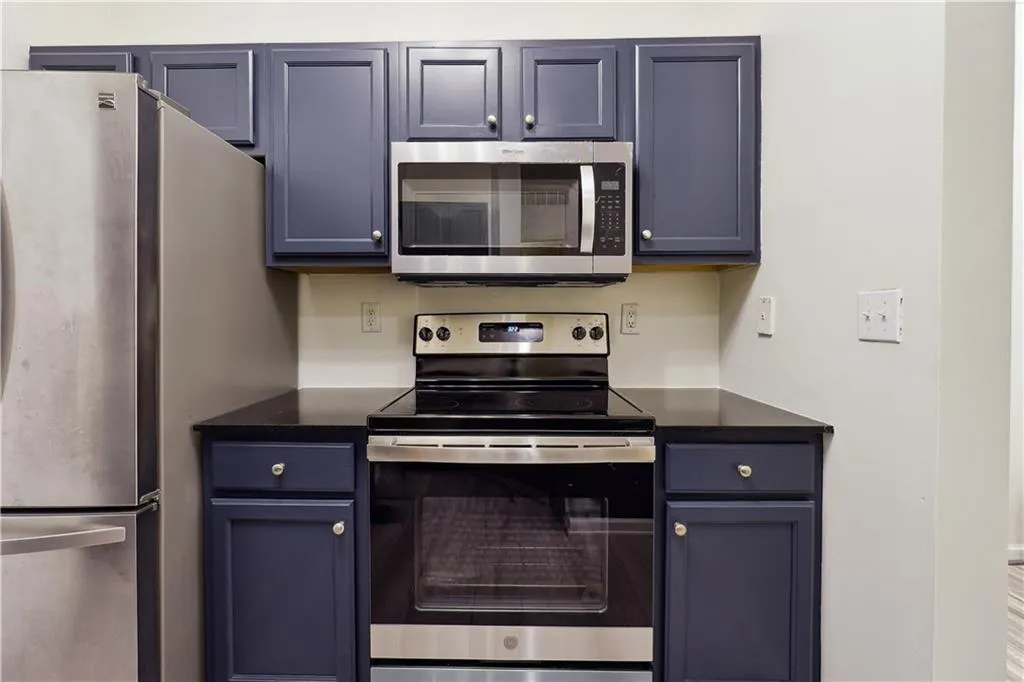 Kitchen featuring blue cabinetry and appliances with stainless steel finishes