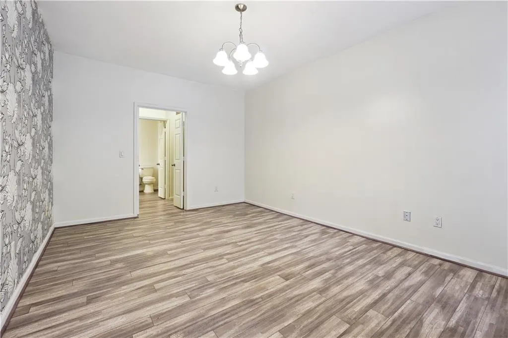 Empty room with light wood-type flooring and a chandelier