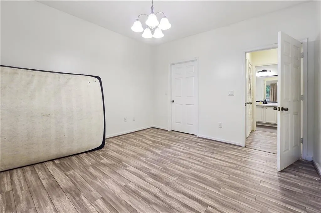 Unfurnished bedroom featuring light hardwood / wood-style floors and a notable chandelier