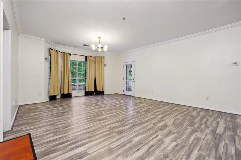 Unfurnished room featuring hardwood / wood-style flooring, an inviting chandelier, and ornamental molding