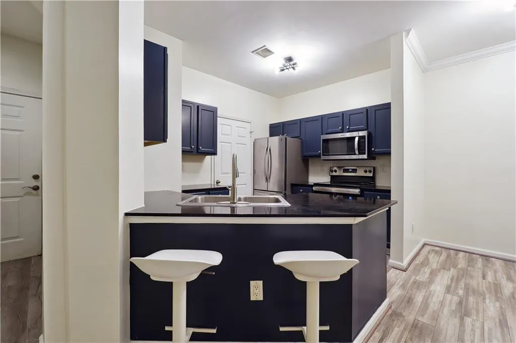Kitchen featuring kitchen peninsula, appliances with stainless steel finishes, ornamental molding, and a breakfast bar area