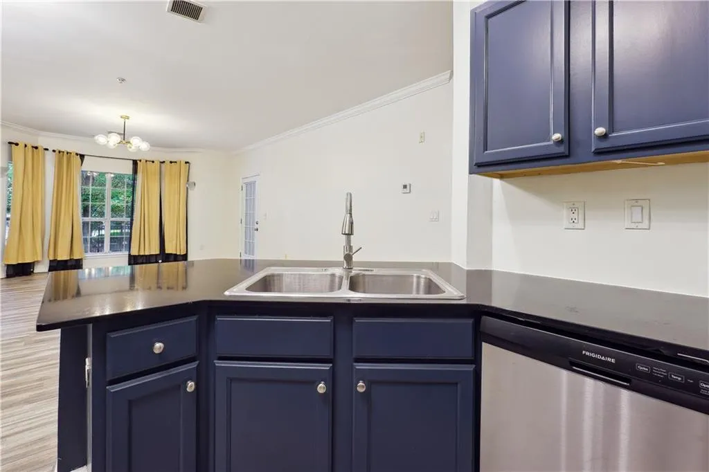 Kitchen with sink, stainless steel dishwasher, a notable chandelier, blue cabinets, and kitchen peninsula