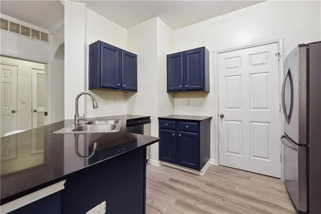 Kitchen with blue cabinetry, sink, stainless steel appliances, and light hardwood / wood-style floors