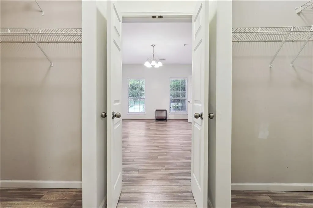 Walk in closet with hardwood / wood-style floors and a chandelier