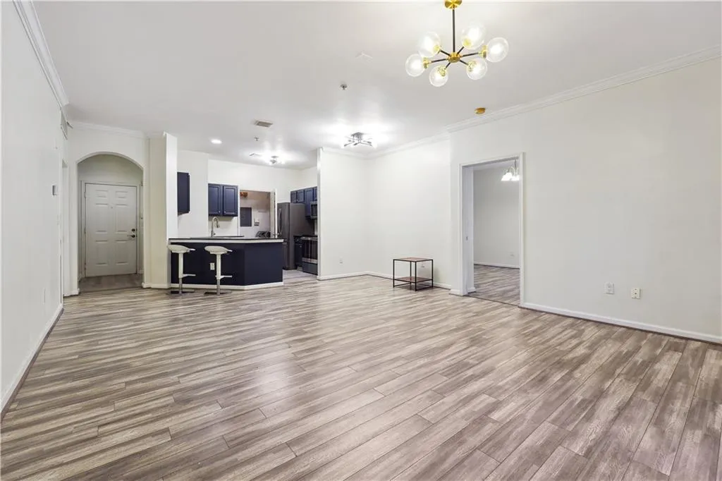 Living room with a notable chandelier, light hardwood / wood-style floors, and ornamental molding