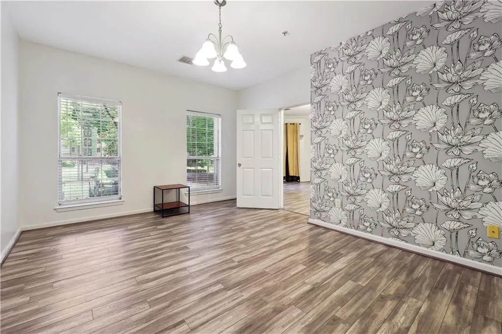 Empty room featuring hardwood / wood-style floors and a notable chandelier