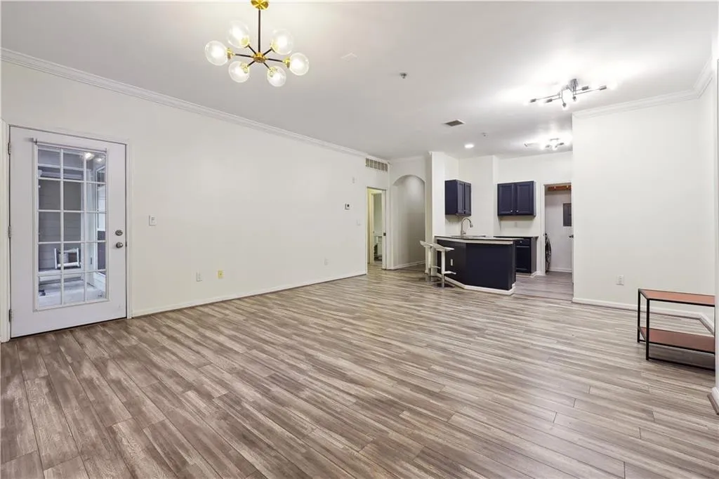 Unfurnished living room with a notable chandelier, ornamental molding, and light hardwood / wood-style flooring