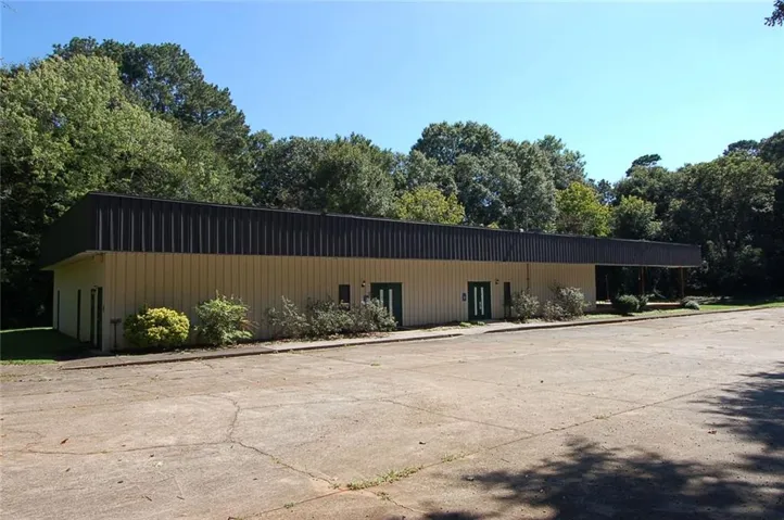 Single-story commercial building with light-colored siding and a dark metal roof