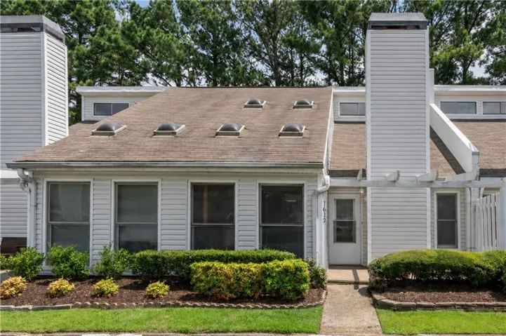 Siding exterior with multiple skylights, prominent chimney, and front landscaping