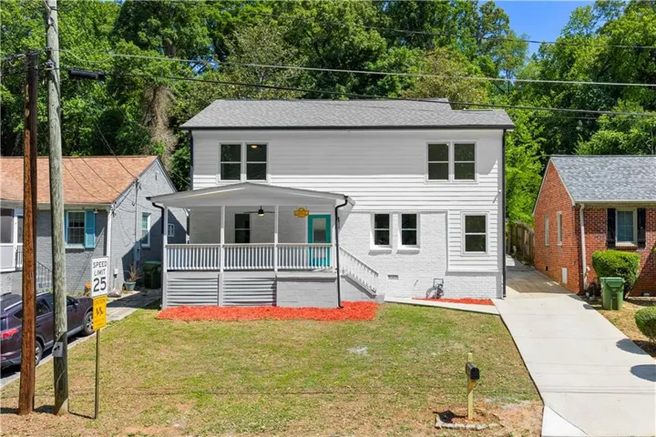 Two-story residence featuring a covered front porch with white railing, a turquoise front door, and a light gray roof