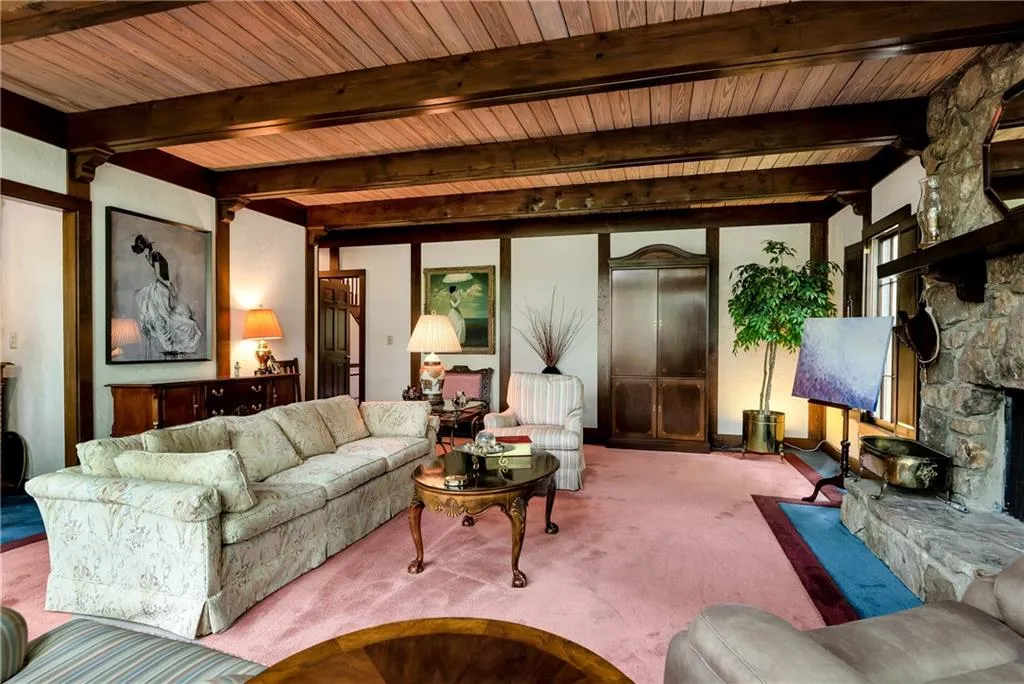 Living room with beamed ceiling, a fireplace, carpet flooring, and wood ceiling