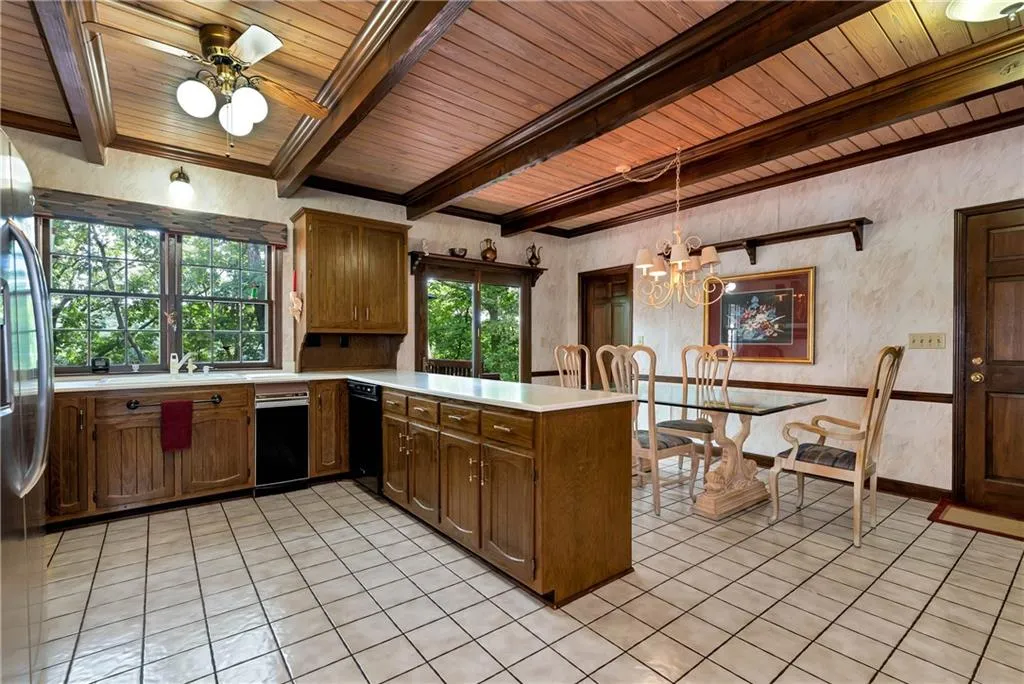 Kitchen with kitchen peninsula, beam ceiling, light tile floors, hanging light fixtures, and wooden ceiling