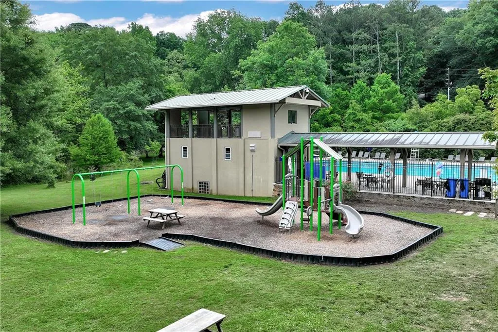 View of playground featuring a community pool and a lawn