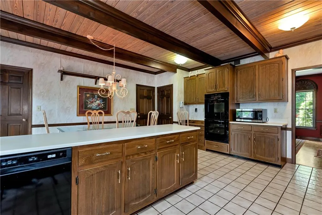 Kitchen featuring beam ceiling, light tile floors, decorative light fixtures, and double oven
