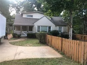 Siding exterior featuring a covered front porch with white railings, a concrete driveway, and a wood picket fence