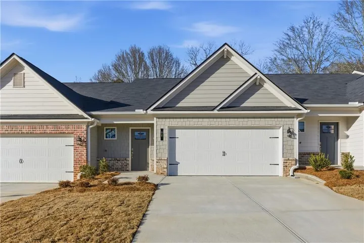 Exterior featuring a two-car garage, brick accents, board and batten siding, shake siding, and a dark front door with window inserts
