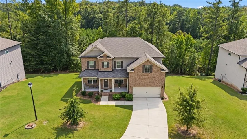 Brick and siding exterior with a covered porch, attached two-car garage, and a concrete driveway