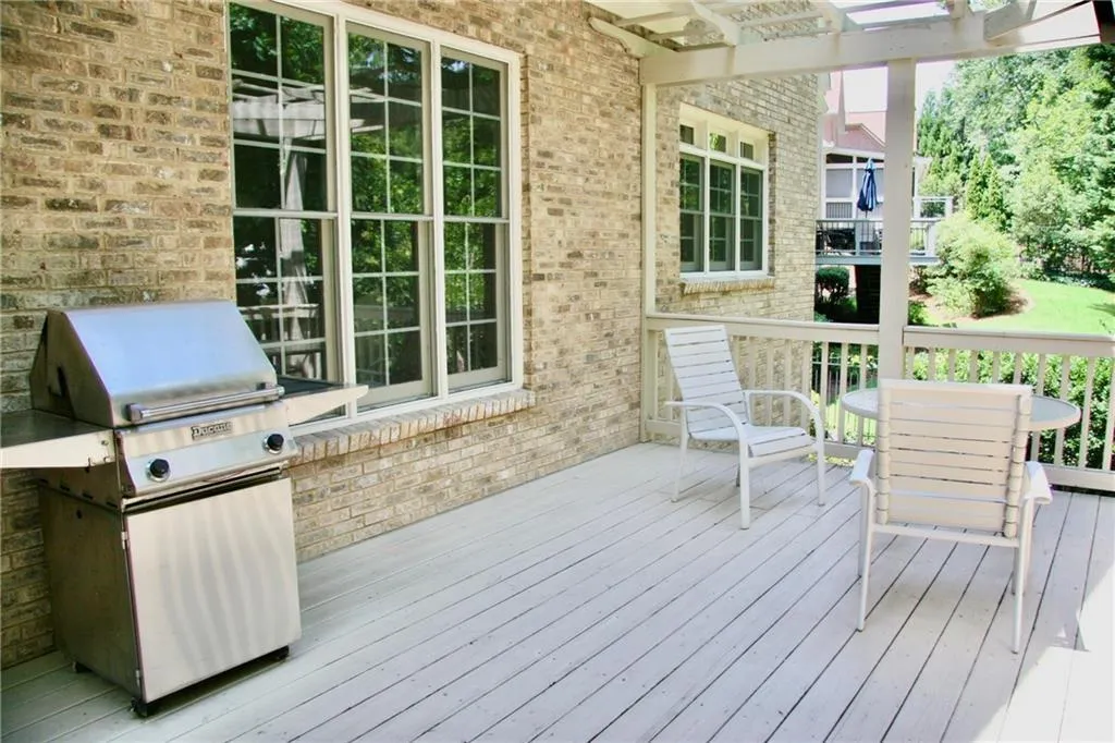 Deck featuring an outdoor kitchen, a pergola, and a grill