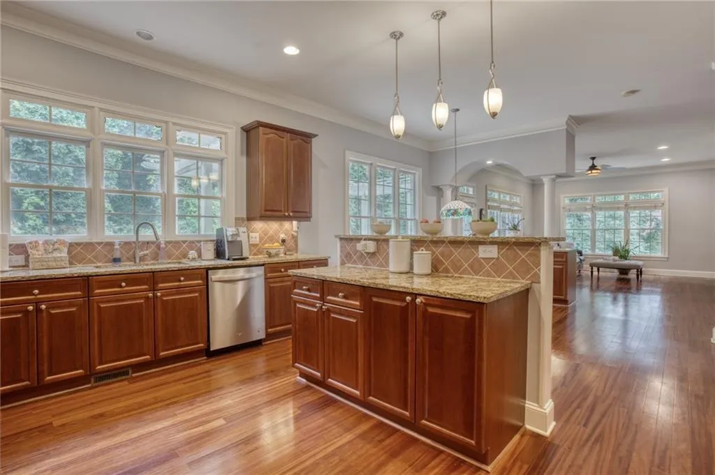 Kitchen featuring a healthy amount of sunlight, decorative backsplash, stainless steel dishwasher, and light hardwood / wood-style flooring