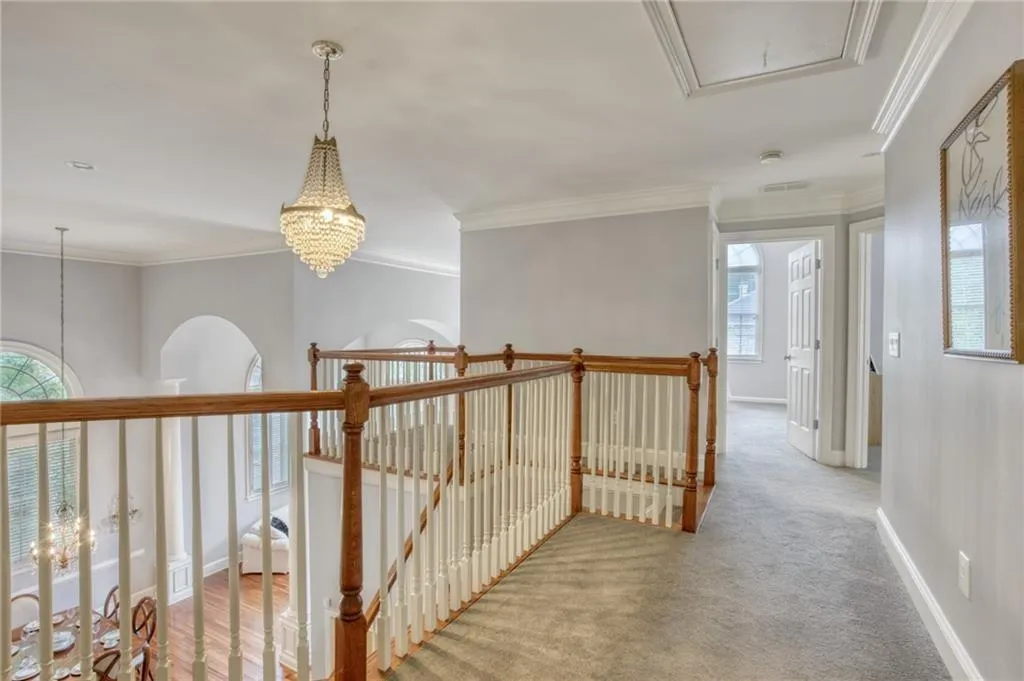Hall featuring carpet, ornamental molding, a chandelier, and a wealth of natural light