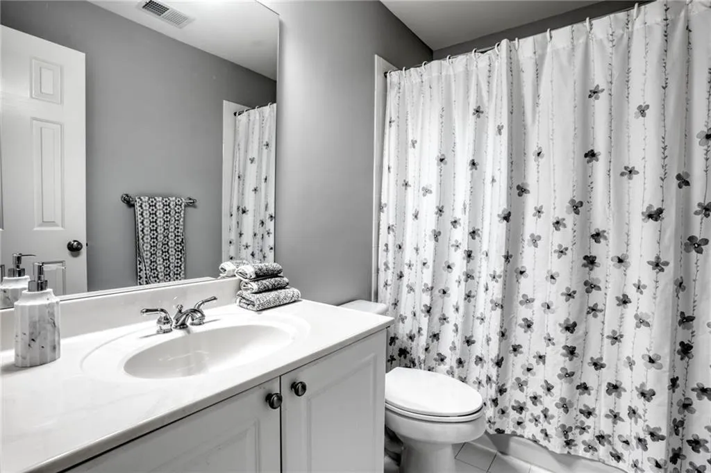 Bathroom 2 of three upstairs with tile patterned flooring, walk in shower, vanity, and toilet