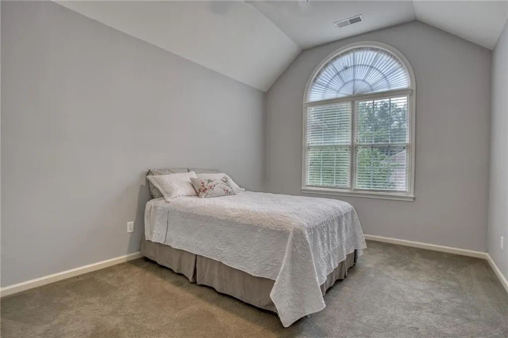 Bedroom 2 of 3 upstairs with carpet floors and vaulted ceiling