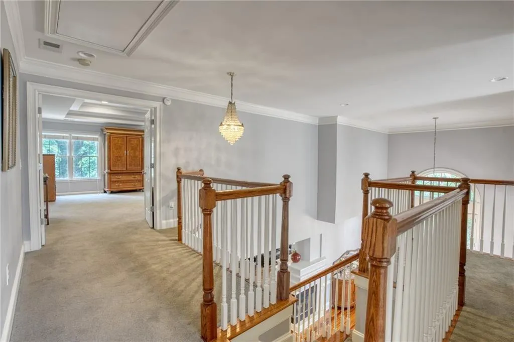 Hallway with light colored carpet and crown molding