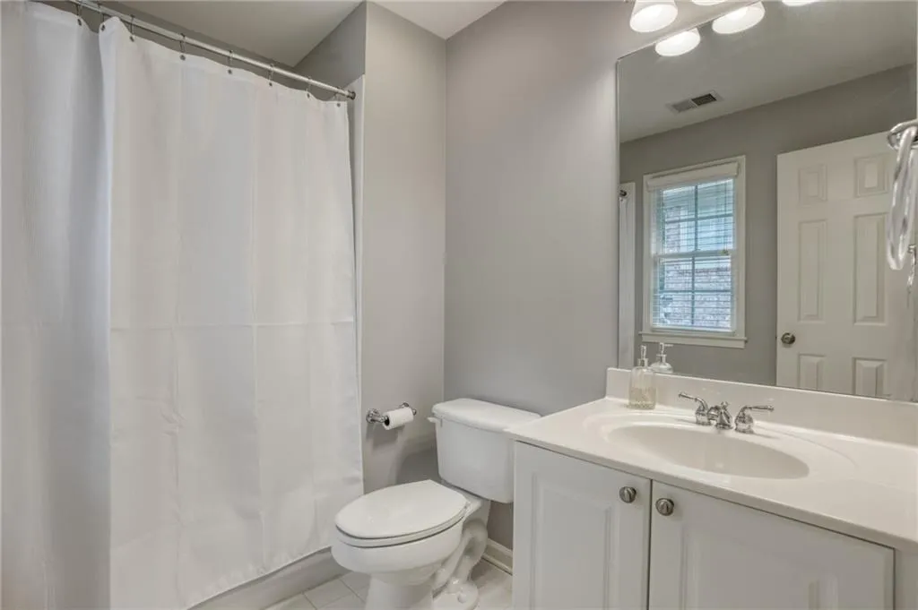 Bathroom with vanity, tile patterned flooring, toilet, and curtained shower