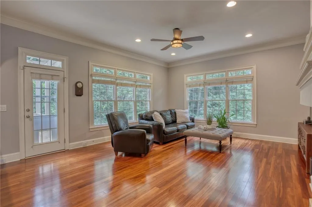 Living room featuring ornamental molding, wood-type flooring, ceiling fan, and plenty of natural light