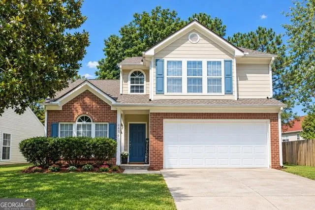 Two-story residence featuring a brick and siding exterior, an attached two-car garage, established front landscaping, and a concrete driveway