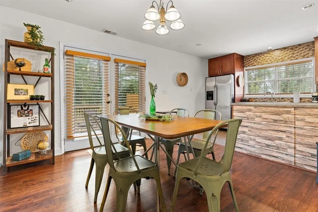 Dining room with healthy amount of natural light, wood finished floors, and a chandelier