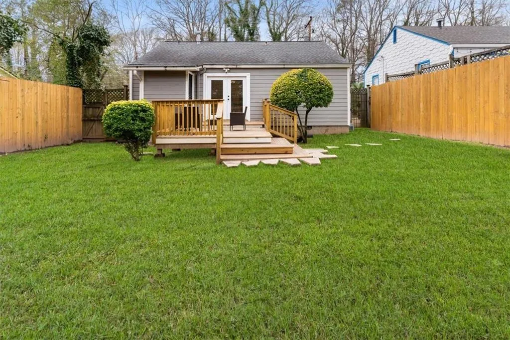 Back of property featuring a deck, french doors, a fenced backyard, roof with shingles, and a gate