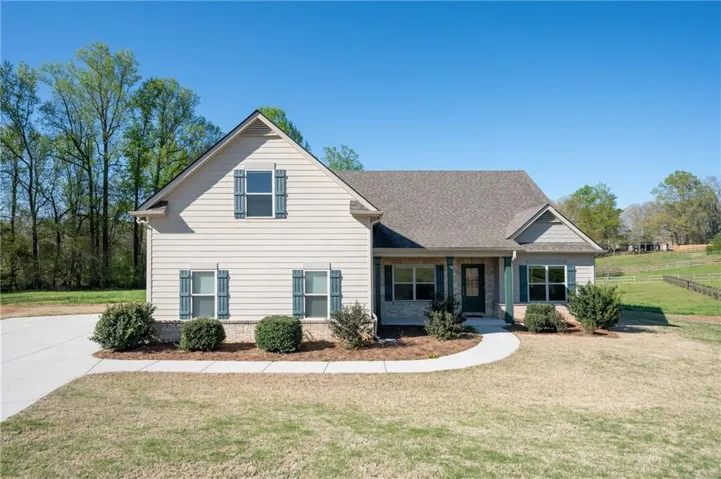 Single-story property featuring light-colored siding, a covered front porch, and a gravel driveway