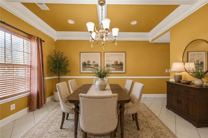 Dining room featuring a tray ceiling with crown molding, recessed lighting, and a chandelier