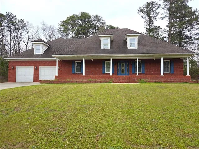 View of front facade featuring a porch, a front yard, driveway, a garage, and brick siding